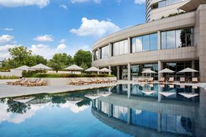 a building with a pool with chairs and umbrellas at Conrad Istanbul Bosphorus in Istanbul