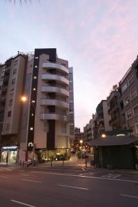 un edificio alto en una calle de la ciudad con edificios en Hotel Madanis, en Hospitalet de Llobregat