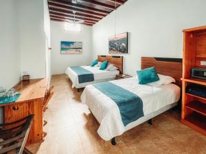 a bedroom with two beds and a desk and a desk at Hotel Albemarle in Puerto Villamil
