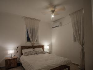 a bedroom with a bed with two lamps and two windows at Appartement cosy sur Netanya in Netanya