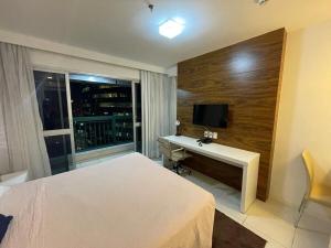 ブラジリアにあるV1117 Lindo flat aconchegante em Hotel de BSBのベッド、デスク、テレビが備わるホテルルームです。