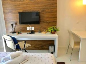 a bedroom with a desk with a tv on a wall at V1118 Maravilhoso flat em hotel de Brasília Central in Brasilia