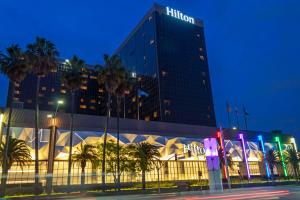 a hilton hotel at night with palm trees in front of it at Hilton Los Angeles Airport in Los Angeles