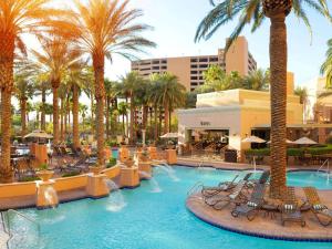a resort swimming pool with chairs and palm trees at Hilton Grand Vacations Club on the Las Vegas Strip in Las Vegas