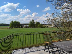 a fence with a table and chairs and a field at Apartament za lasem in Kaliska Kośierskie