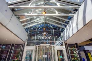 un bâtiment en verre avec un panneau hilton sur celui-ci dans l'établissement Hilton Leeds City, à Leeds