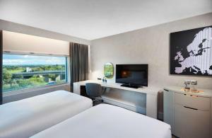 a hotel room with two beds and a flat screen tv at Hilton London Heathrow Airport in Hillingdon