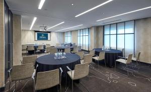 a conference room with tables and chairs and a screen at Hilton London Heathrow Airport in Hillingdon