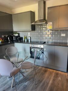 uma cozinha com uma mesa de vidro e cadeiras em Transformative housing 6 Bedford em Derby