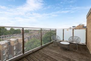 - un balcon avec deux chaises et une table dans un bâtiment dans l'établissement Hilton London Kensington Hotel, à Londres