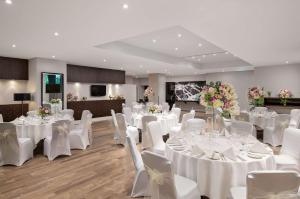 um salão de banquetes com mesas brancas e cadeiras brancas em Hilton London Kensington Hotel em Londres