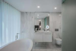 een witte badkamer met een bad en een toilet bij DoubleTree by Hilton Lisbon Fontana Park in Lissabon