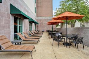 uma fila de cadeiras e mesas com guarda-sóis num pátio em Embassy Suites Little Rock em Little Rock