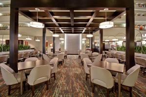 Embassy Suites Little Rock في ليتل روك: غرفة طعام مع طاولات وكراسي بيضاء