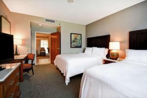 a hotel room with two beds and a television at Embassy Suites Little Rock in Little Rock