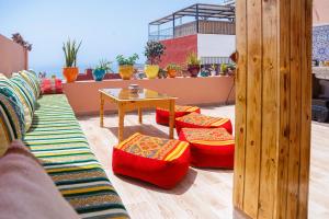 Un patio con sillas y una mesa en un tejado. en Atlantic Vibes Surf Hostel, en Tamraght Ouzdar