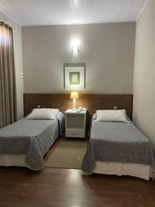 a bedroom with two beds and a table with a lamp at Canasvieiras Hotel in Florianópolis