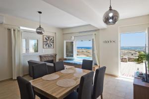 una sala da pranzo con tavolo, sedie e vista sull'oceano di Vènto villa a Karpathos