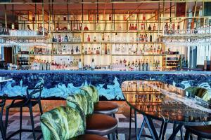 a bar with green chairs and a counter with alcohol bottles at DoubleTree by Hilton Hotel London - Tower of London in London