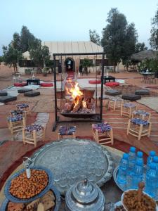 メルズーガにあるMerzouga Majestic Campのたくさんの食べ物とテーブルが置かれた焚き火台