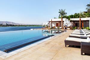 - une piscine avec des chaises longues à côté d'un complexe dans l'établissement Hilton Luxor Resort & Spa, à Louxor