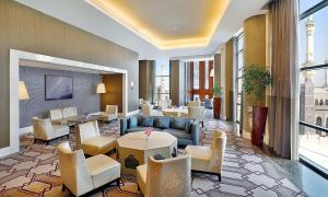 un vestíbulo con sofás, mesas y sillas en Hilton Suites Makkah, en La Meca