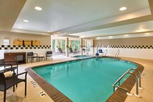 una piscina en una habitación de hotel con sillas y mesa en Hilton Garden Inn Hershey en Hummelstown