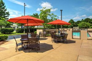 eine Terrasse mit Tischen, Stühlen und roten Sonnenschirmen in der Unterkunft Hampton Inn & Suites Memphis-Wolfchase Galleria in Memphis