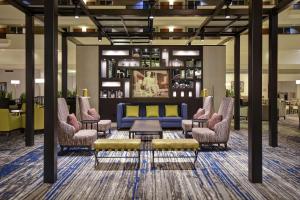 a lobby with a blue couch and several chairs at Embassy Suites Montgomery - Hotel & Conference Center in Montgomery