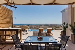 eine Terrasse mit einem Tisch, Stühlen und einem Pool in der Unterkunft Vènto villa in Karpathos