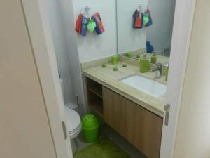 a bathroom with a sink and a toilet and a mirror at Departamento resort lagunas del mar in La Serena