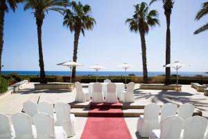 a wedding aisle with white chairs and palm trees at Hilton Malta in St Julian's