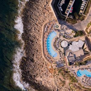 an overhead view of the pool at a resort next to the ocean at Hilton Malta in St Julian's