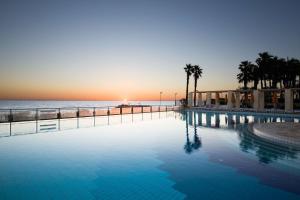 a swimming pool at the beach at sunset at Hilton Malta in St Julian's