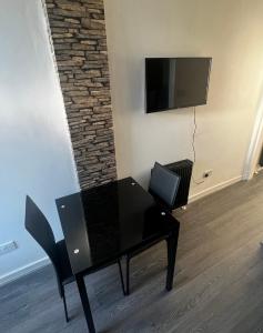 a black table with a chair and a television on a wall at AP Apartment in Glasgow