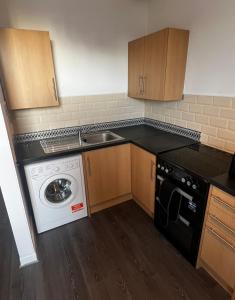 a kitchen with a sink and a washing machine at AP Apartment in Glasgow