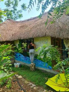 a woman standing outside of a house with a thatch roof at Cabañas Mannan in Tanchachín