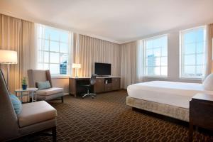 ニューオーリンズにあるヒルトン ニューオーリンズ セントチャールズ アベニューのベッド、デスク、椅子が備わるホテルルームです。
