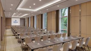 una fila di tavoli e sedie in una stanza di Hilton Munich City a Monaco