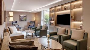 a hotel lobby with chairs and tables and a flat screen tv at Hilton Munich City in Munich