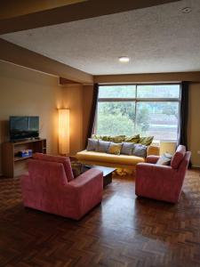 a living room with two red chairs and a couch at Tin House Quito in Quito