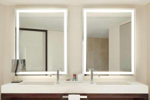 a bathroom with two sinks and two mirrors at Conrad New York Downtown in New York