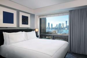 a bedroom with a large white bed and a large window at Conrad New York Downtown in New York