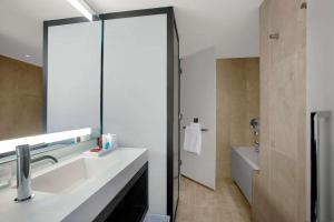 a bathroom with a sink and a mirror and a tub at Conrad New York Downtown in New York