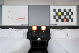 two beds in a hotel room with white pillows at Conrad New York Downtown in New York