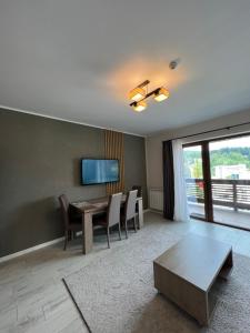 a living room with a table and chairs and a television at Apartamente de inchiriat- Garden Apart Predeal in Predeal