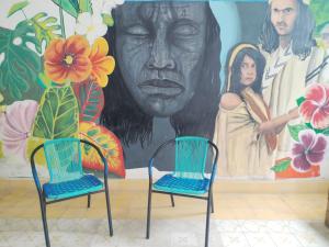 two chairs in front of a wall with a mural at HOSTEL LA CASA DE PETRA in Santa Marta