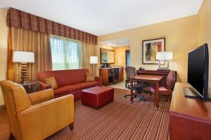 una sala de estar con sofá y escritorio en una habitación de hotel en Embassy Suites by Hilton Norman Hotel & Conference Center en Norman