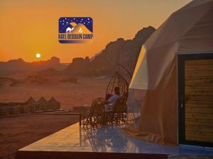 a man sitting in a tent in the desert at sunset at Nael Bedouin camp in Wadi Rum