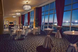 una sala de conferencias con mesas, sillas y ventanas grandes en Hilton Omaha, en Omaha